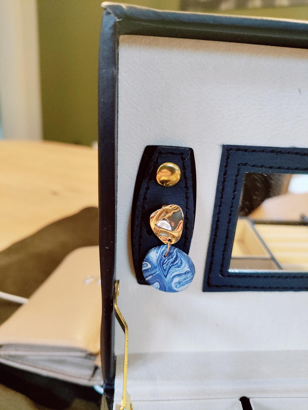 Detail van een ronde blauw gemarmerde oorbel met goudkleurige steker
